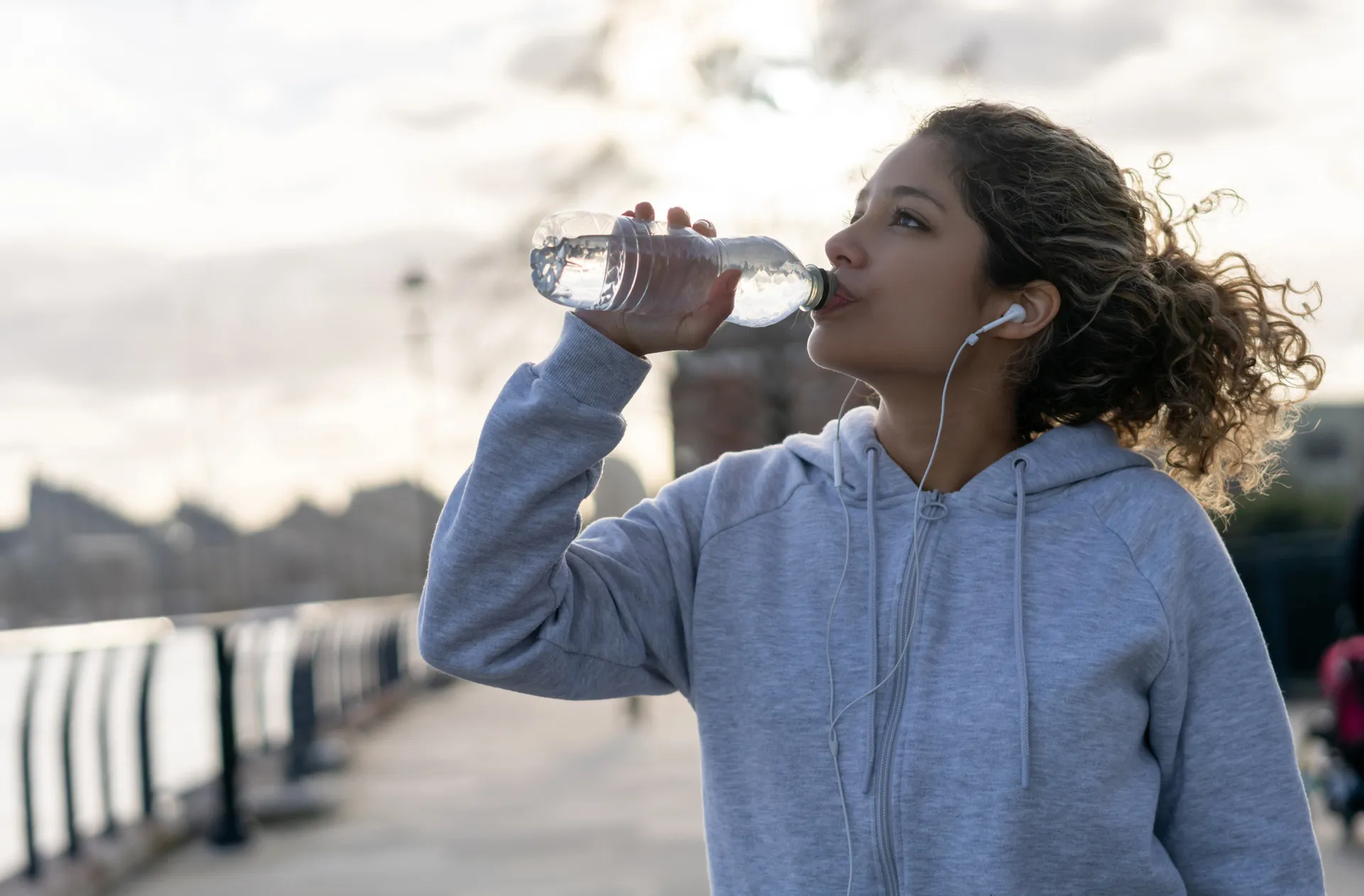 Woman drinking water while running outdoors