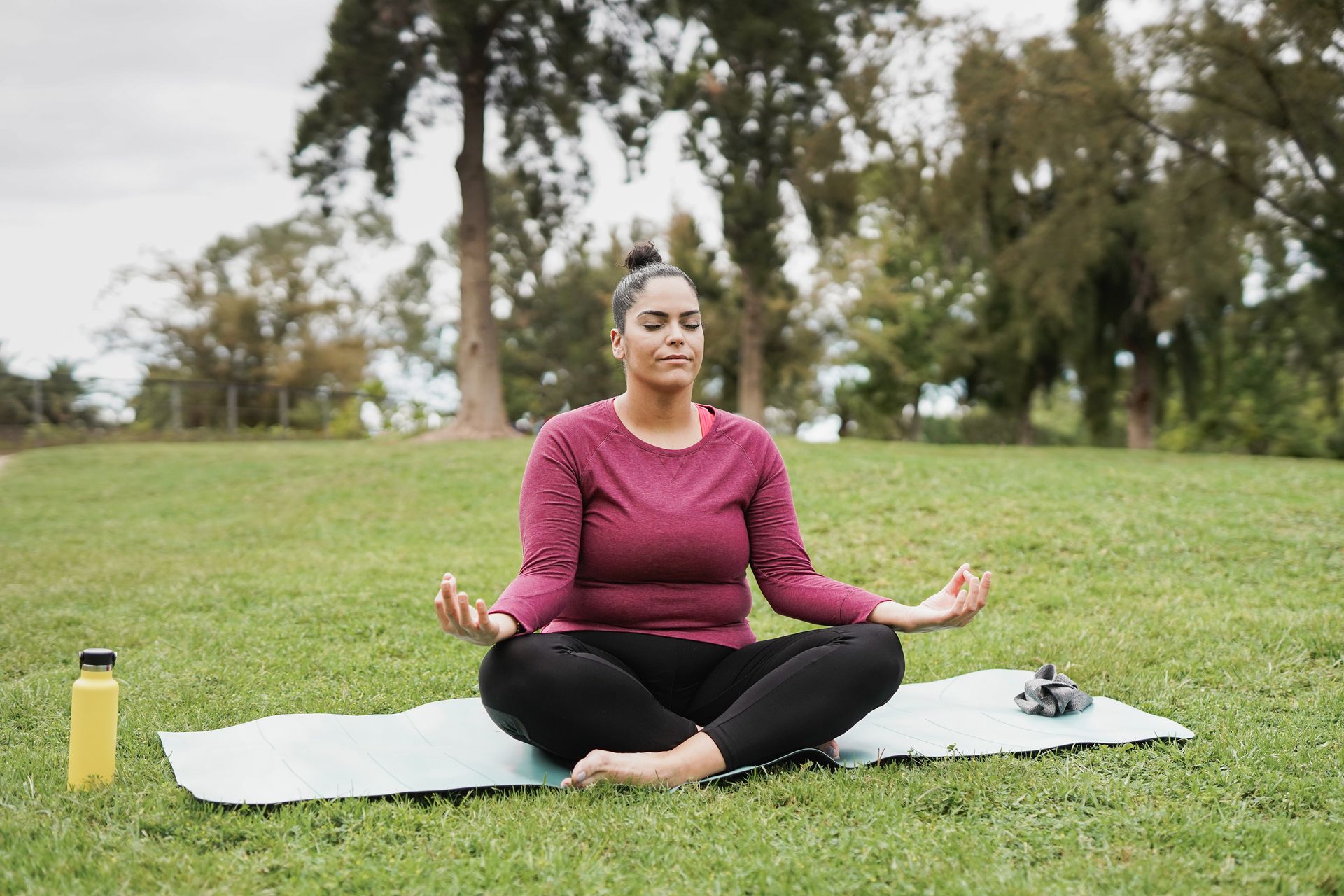 woman doing meditation at city park - Healthy lifestyle and life balance concept