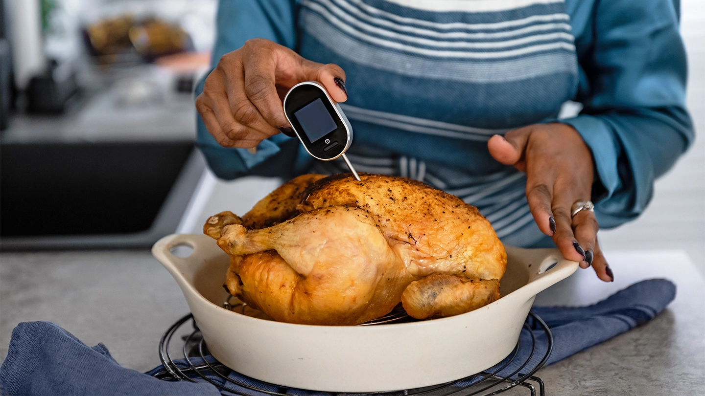 Women taking internal temperature of cooked chicken